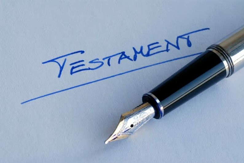 Füllfederhalter liegt auf Papier mit handschriftlichem Wort 'TESTAMENT'