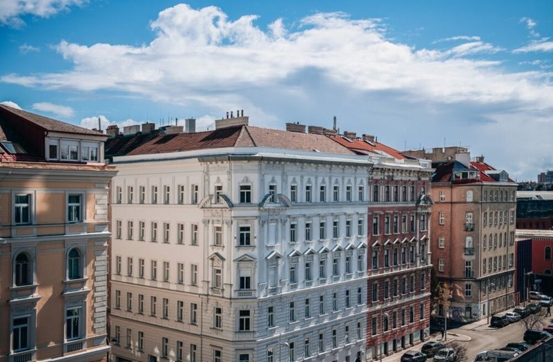 Mehrere mehrstöckige Altbauten mit Fassadendetails unter blauem Himmel mit Wolken