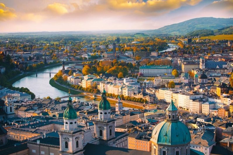 Luftaufnahme einer Stadt mit Fluss, Brücken und historischen Gebäuden im Herbstlicht