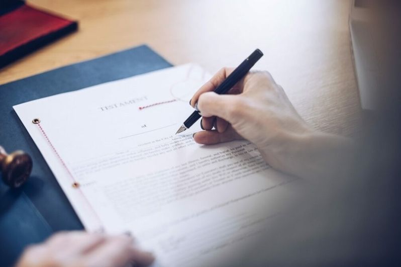 Hand hält Stift und unterschreibt Dokument